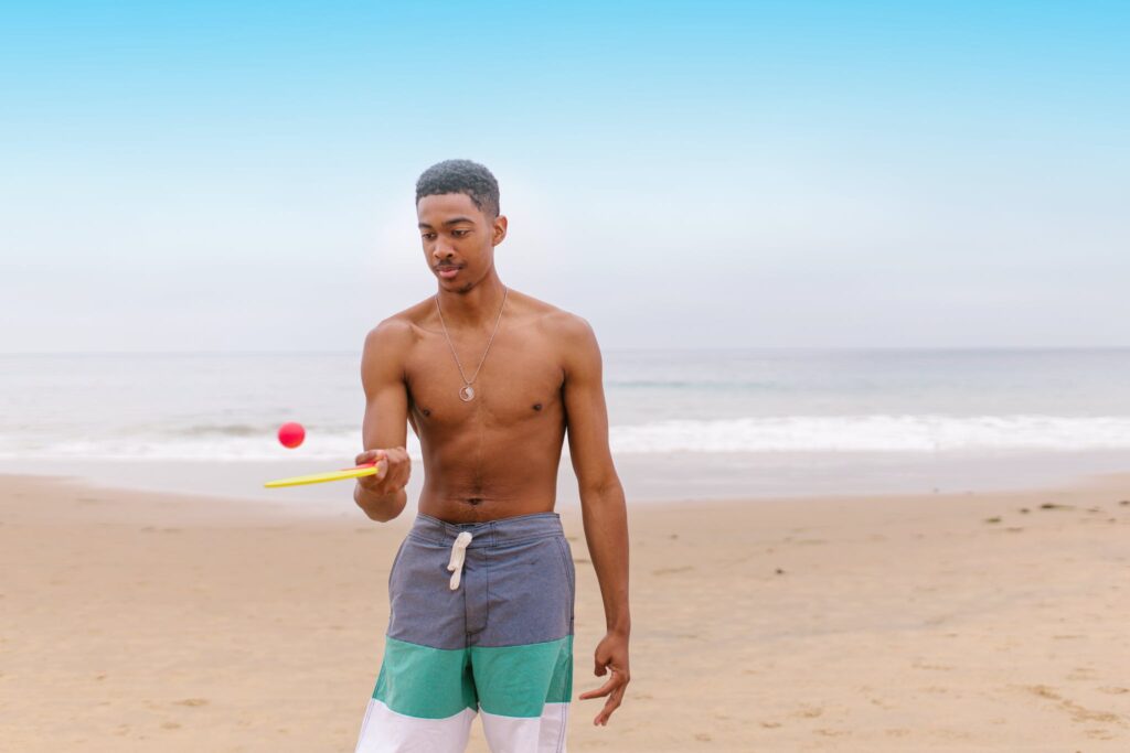 A Man Playing with a Ping Pong Ball at the Beach